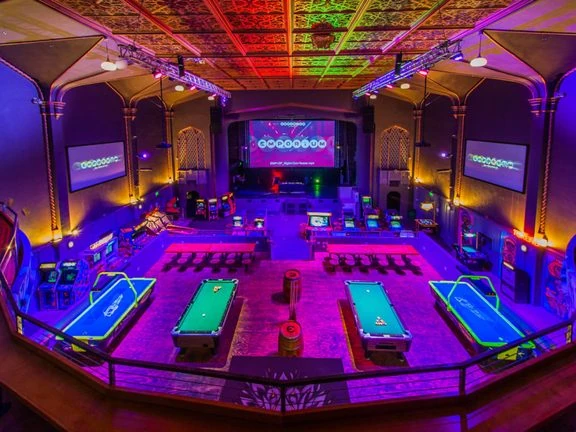 The main hall at Emporium Arcade Bar, with arcade games and pool tables under a decorative ceiling